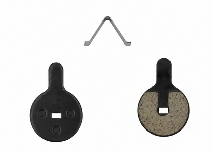 Two round black target discs with a square cutout, one showing the back with three screw holes and one showing the front with a textured insert, plus a small V-shaped metal clip at the top on a white background.
